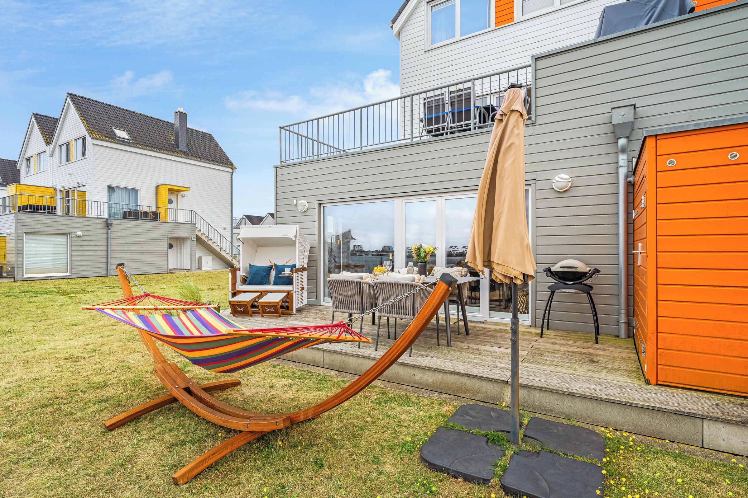 A residential backyard with a hammock, outdoor furniture, and a barbecue area.