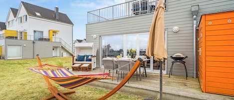 A residential backyard with a hammock, outdoor furniture, and a barbecue area.