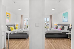 Une pièce aux murs recouverts de miroirs, avec deux lits, une fenêtre et une vue sur l’extérieur.