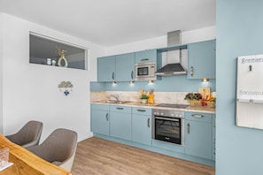 A modern kitchen with light blue cabinets, a Bosch oven, and a microwave. - Fischerman's Friend - First row on the waterfront, infrared sauna, 3 TVs, close to the beach (Olpenitz)