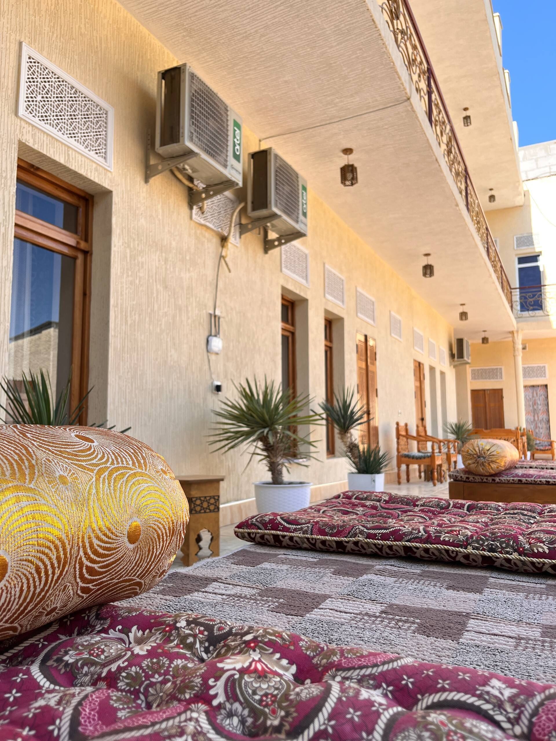A hotel corridor with air conditioning units, potted plants, and traditional furniture.