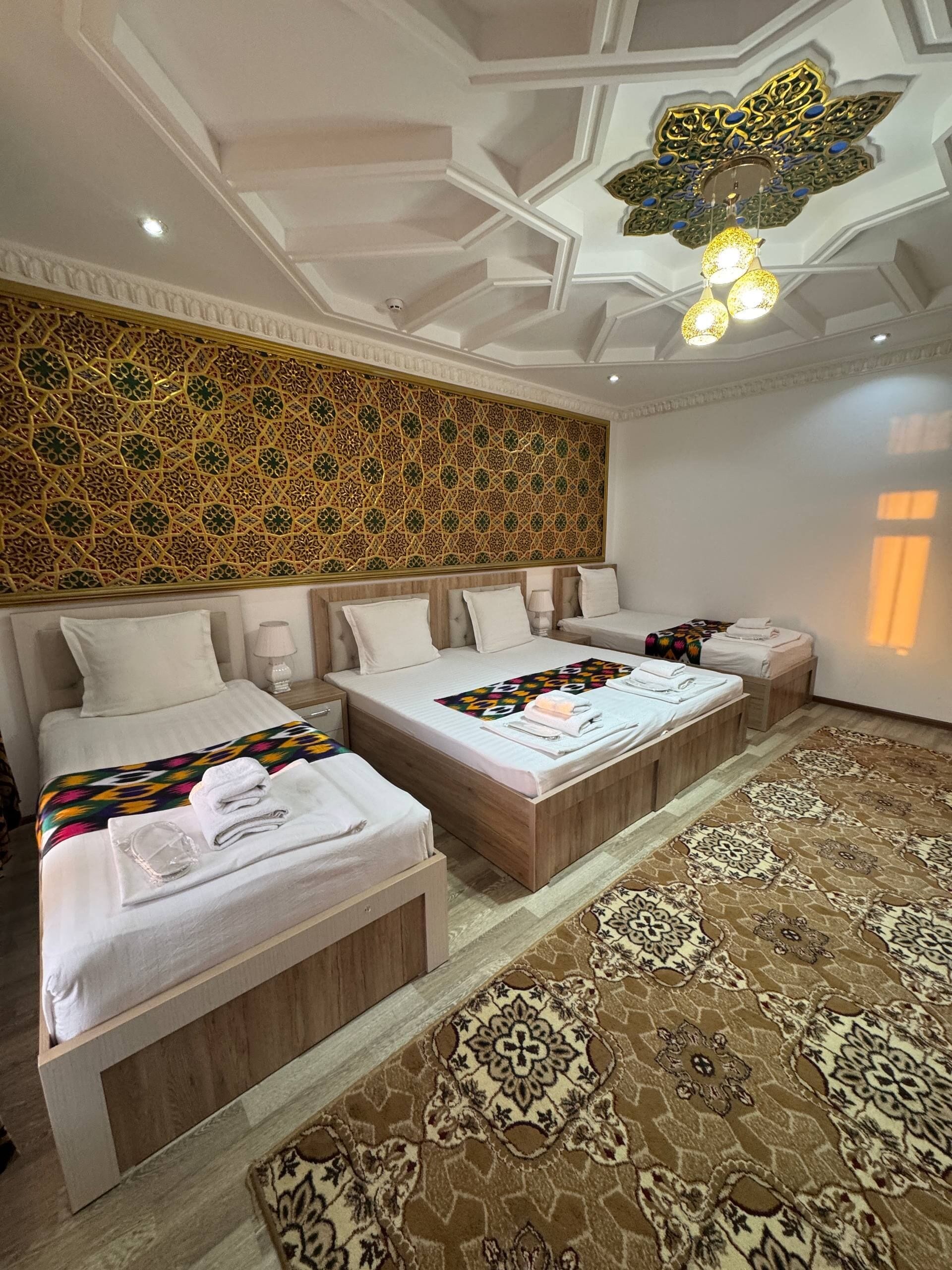 A hotel room with a large bed, a smaller bed, a decorative wall, and a patterned carpet.