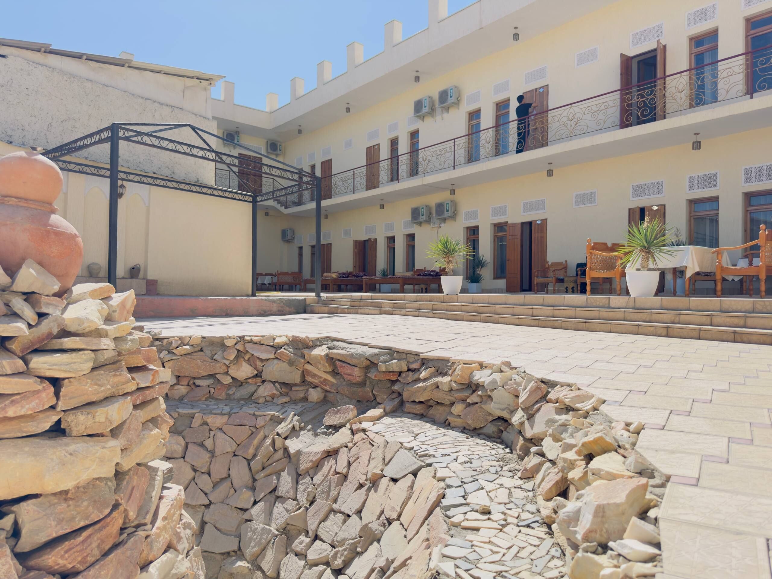 Un patio con una fuente de piedra, mobiliario exterior y un edificio con varios balcones.