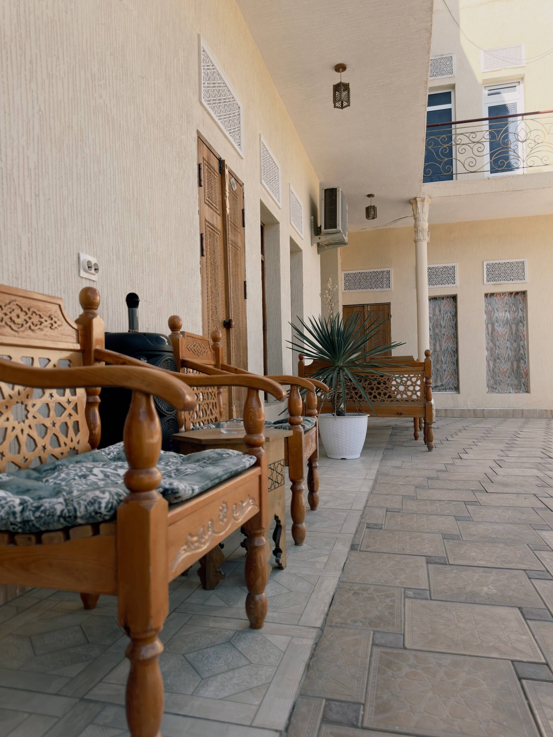 A covered outdoor seating area with wooden furniture and a potted plant.