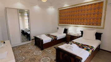 A hotel room with two beds, a large mirror, a patterned carpet, and a ceiling with decorative elements.