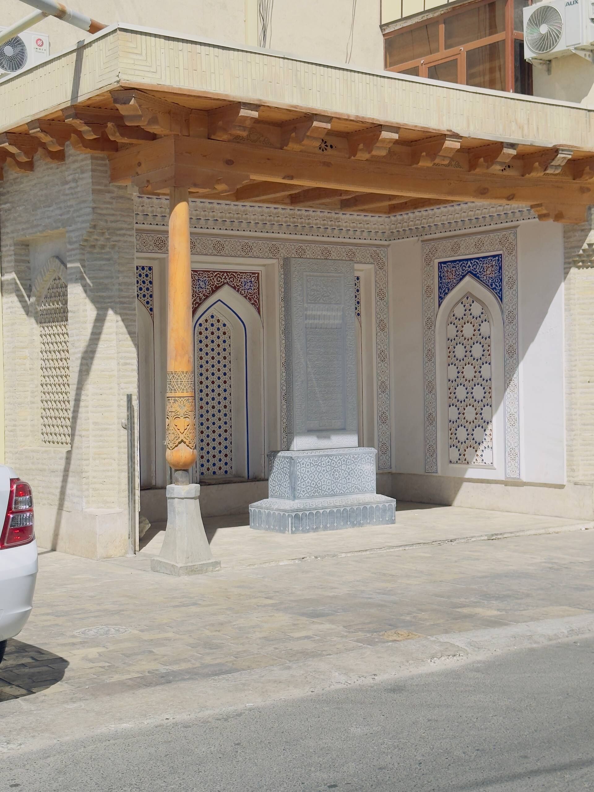 A building entrance with intricate tile work and a wooden column.