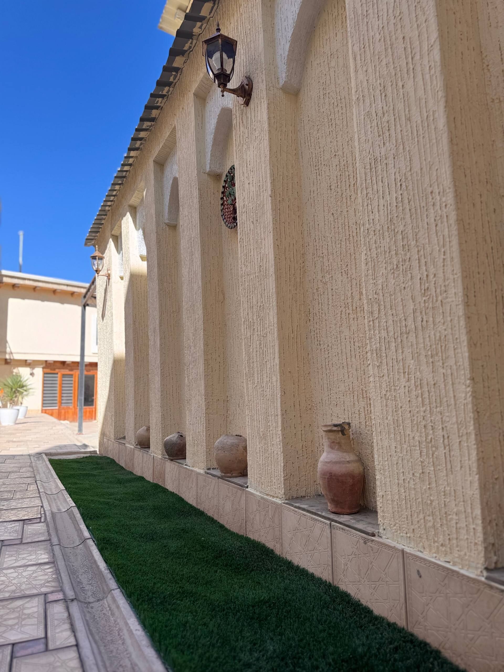 A building with a tiled floor, a green lawn, and decorative vases on the wall.
