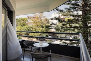 A balcony with a table and chairs, overlooking a residential area with trees and buildings.