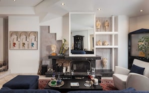 A modern living room with a fireplace, a large mirror, and a bookshelf.