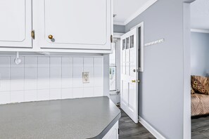 Una cocina con gabinetes blancos, encimera gris y salpicadero de azulejos blancos.