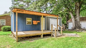 A small, single-story wooden structure with a porch, a door, and a window. - Charming Single-Family Home (Greenville)