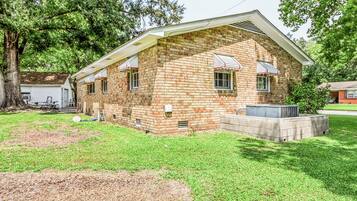 Une maison à deux étages, construite en briques, avec un porche à l’avant, un petit garage attenant et une pelouse bien entretenue.