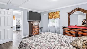 A bedroom with a bed, dresser, TV, and a walk-in closet.
