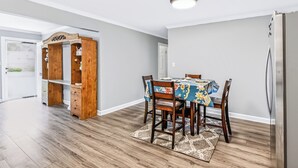 A dining area with a table set for four, surrounded by chairs, a wooden cabinet, and a refrigerator. - Charming Single-Family Home (Greenville)