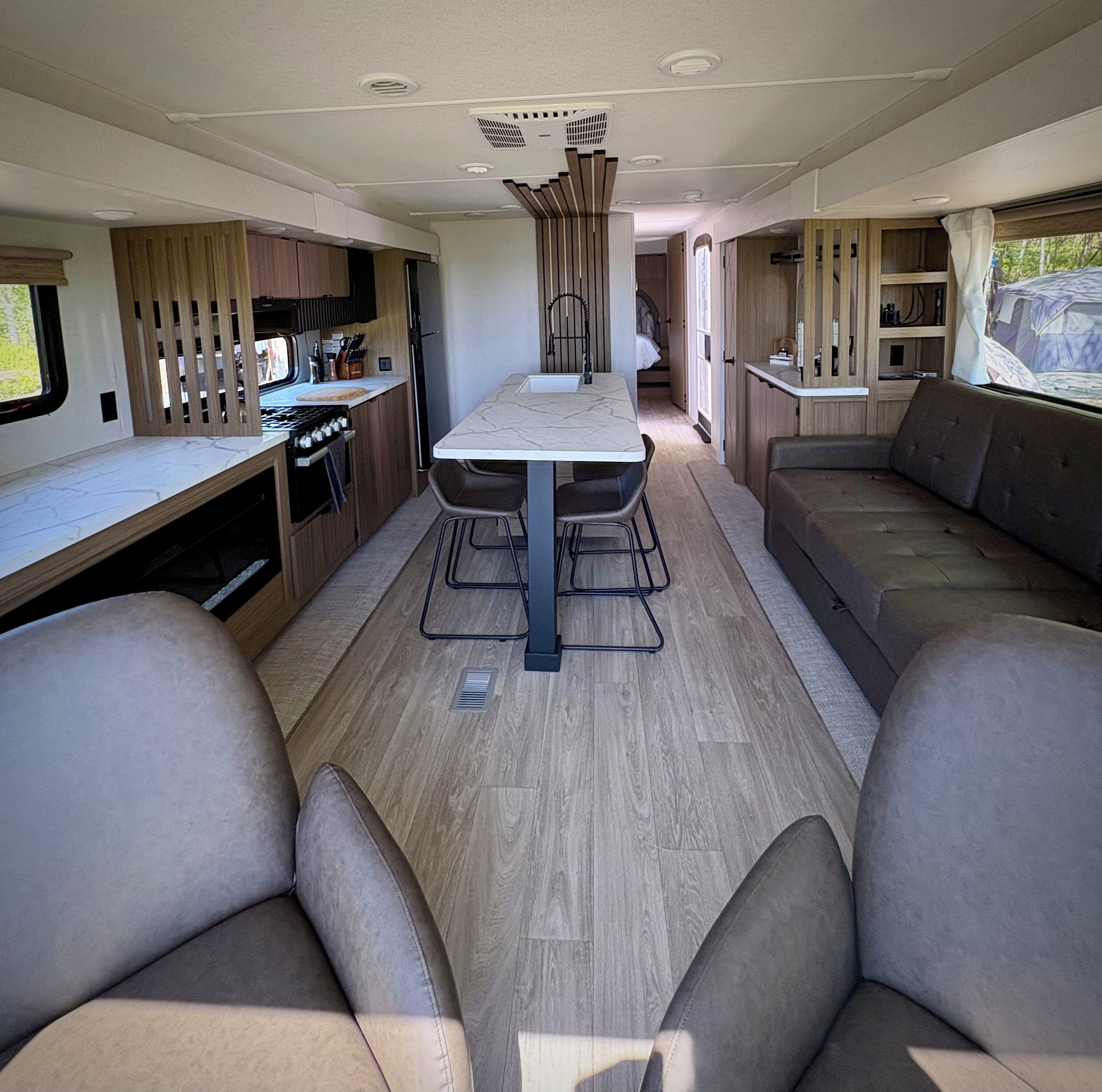 Ein kompaktes Wohnmobil-Interieur mit Küchenzeile, Esstisch und Sitzecke.