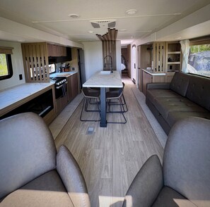 Ein kompaktes Wohnmobil-Interieur mit Küchenzeile, Esstisch und Sitzecke.