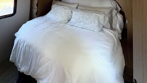 A bed with white linens in a room with wooden paneling and a window. - Private Bay of Fundy Escape | Ocean Views, Sauna & Tides (Upper Rockport)