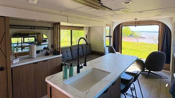 Une cuisine compacte équipée d’un évier, de tabourets de bar et offrant une vue sur l’extérieur.
