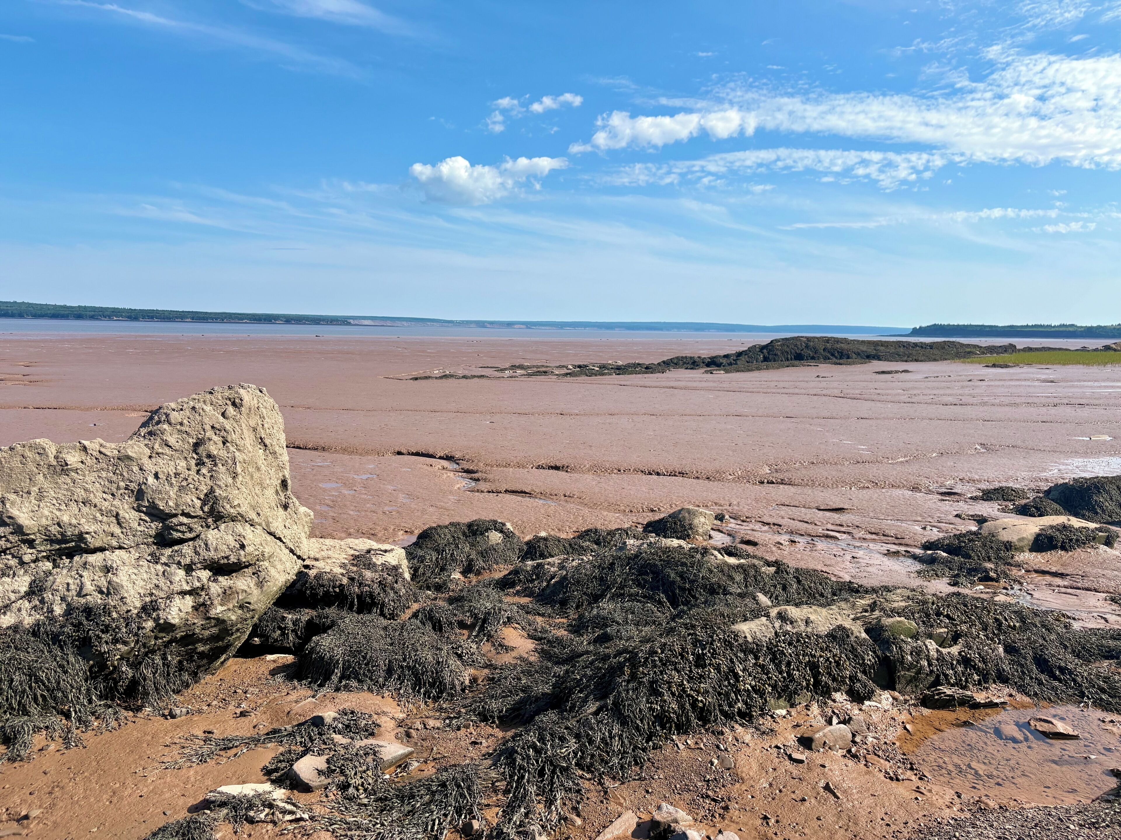 A coastal landscape with rocky terrain and a distant view of the sea.