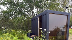 A modern structure with a large glass window, surrounded by a lush garden with various wildflowers.