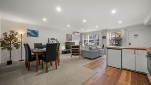 A modern living space with a dining area, a sofa, a kitchen, and a view of the outside. - Chase & Chill  stay in Phillip! (Phillip)