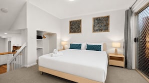 A hotel room with a large bed, two bedside tables with lamps, a wardrobe, and two abstract paintings on the wall. - Chase & Chill  stay in Phillip! (Phillip)