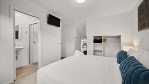 Ein Hotelzimmer mit einem Bett, einem Fernseher, einem Kleiderschrank und einem Badezimmer mit einem Waschbecken.