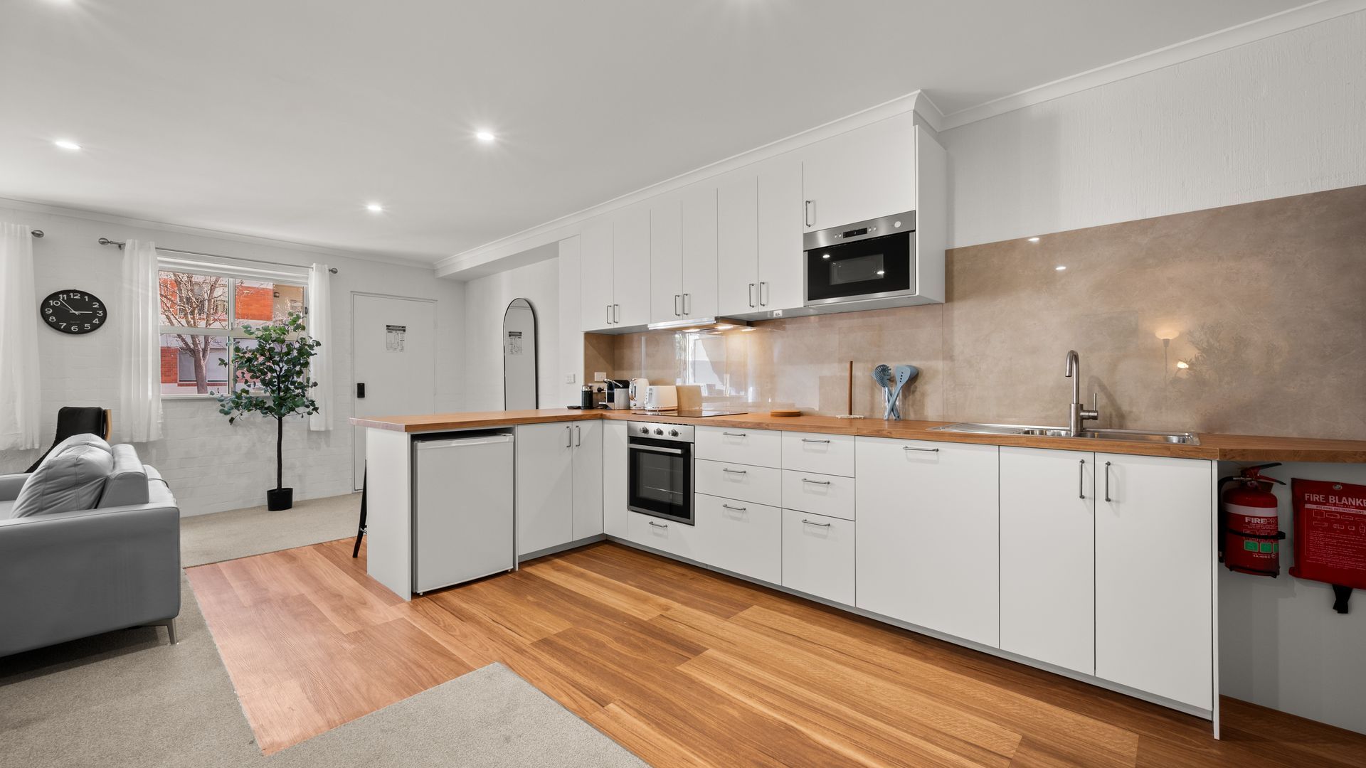 A modern kitchen with white cabinetry, a wooden countertop, and a stainless steel oven.