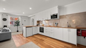Una cocina moderna con armarios blancos, encimera de madera y horno de acero inoxidable.