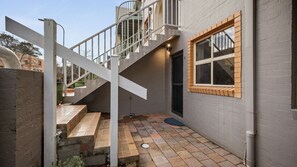A residential property with a staircase leading to a balcony, a small outdoor seating area, and a window with a wooden frame. - Chase & Chill  stay in Phillip! (Phillip)