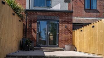 A residential building with a brick facade, a glass door entrance, and a wooden fence.