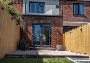 Un immeuble résidentiel avec une façade en briques, une entrée dotée d’une porte en verre et une clôture en bois.