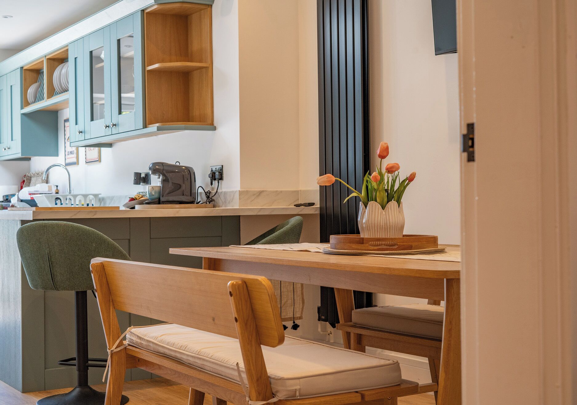 A modern kitchen with wooden cabinets, a dining table, and a bench.