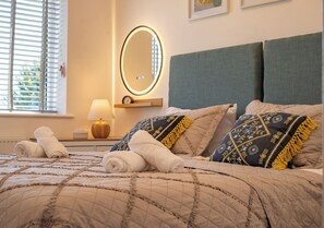 Un lit bien fait, avec des serviettes pliées, une lampe de chevet et un miroir fixé au mur.