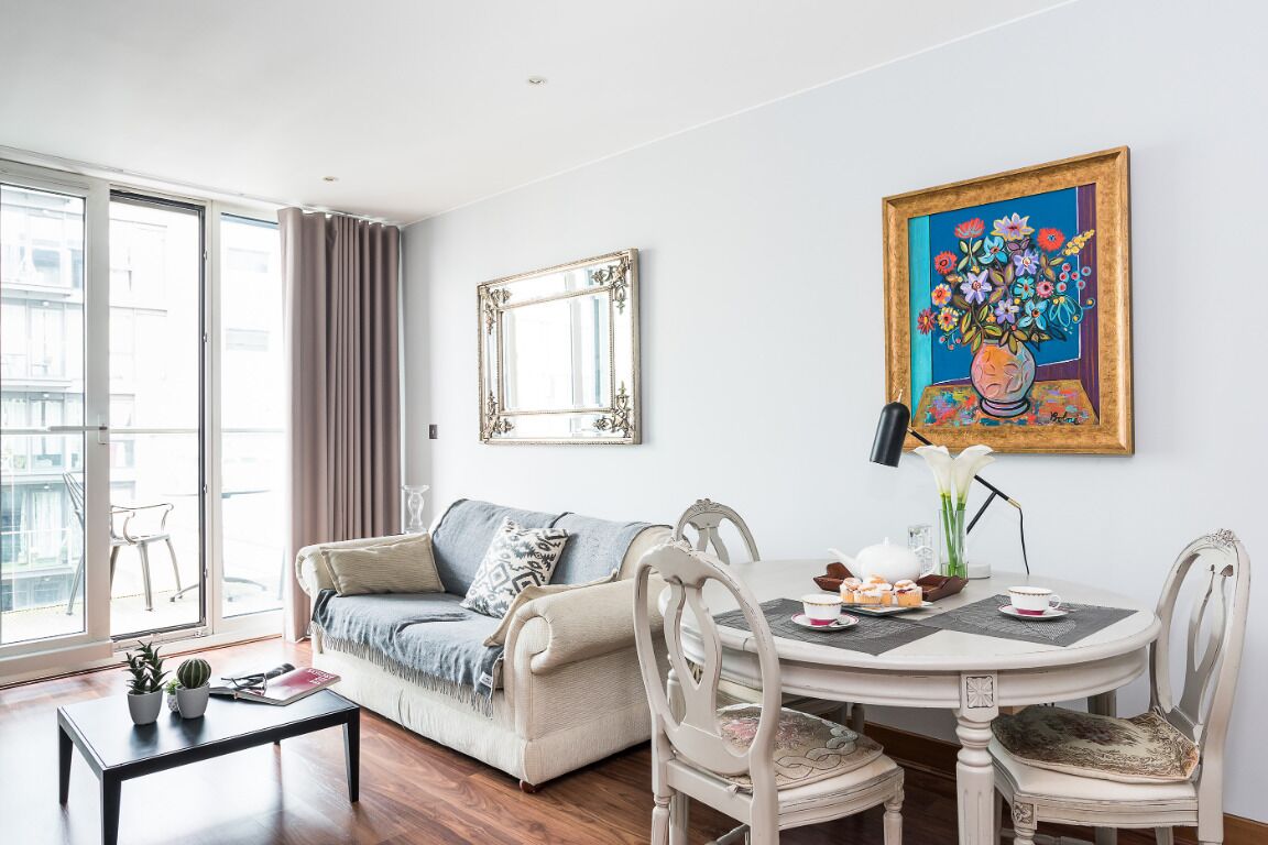 Ein modernes Wohnzimmer mit einer Couch, einem Esstisch mit Stühlen, einem Couchtisch und einem großen gerahmten Gemälde.