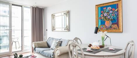Un salon moderne comprenant un canapé, une table à manger avec des chaises, une table basse et un grand tableau encadré.