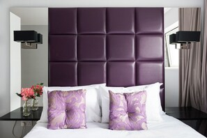 A hotel room with a tufted headboard, two bedside tables, and a bed with white bedding and decorative pillows. - Modern apartment in a prestigious riverside development in Chelsea Bridge Wharf. (London)