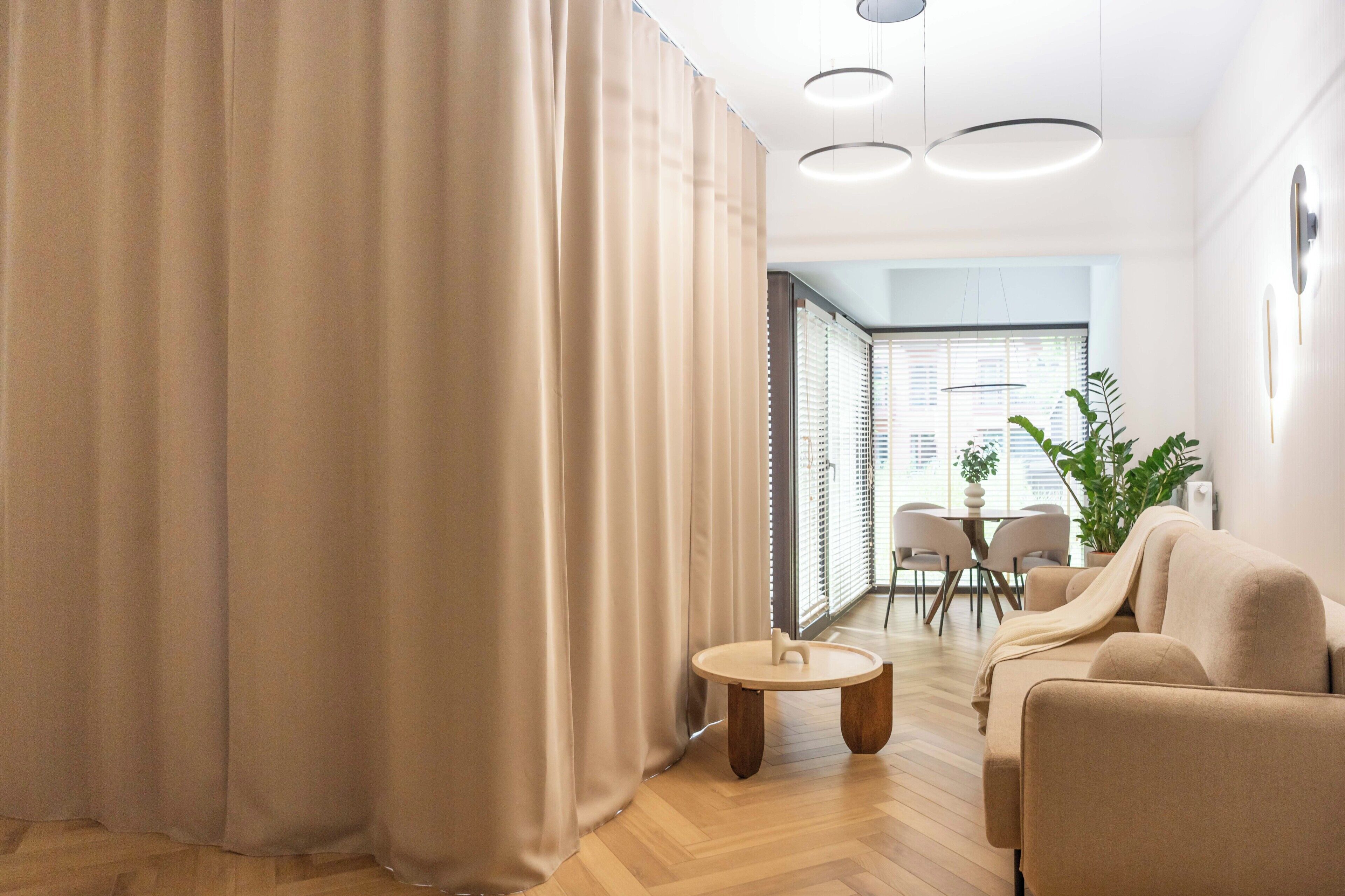 Una sala moderna con un sofá, una mesita redonda y un comedor con mesa y sillas.