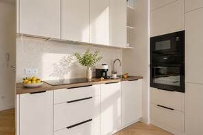 A modern kitchen with a built-in oven, a coffee maker, and a bowl of lemons on the counter. - Granaria Premium with Jacuzzi and Patio (Gdańsk)