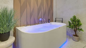Ein modernes Badezimmer mit einer freistehenden Badewanne, einer Wandverkleidung aus Holz und zwei Topfpflanzen.