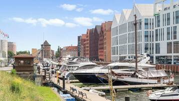 A marina with boats docked, a tower, and modern buildings in the background.
