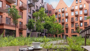 Ein Innenhof mit modernen Wohngebäuden, einem Tisch mit Tasse und Untertasse sowie einem Stuhl.