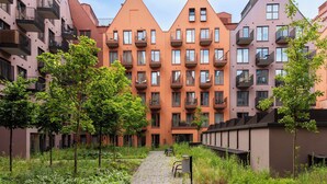 Eine Reihe moderner Apartmenthäuser mit Balkonen, einem zentralen Weg und umliegender Grünfläche.
