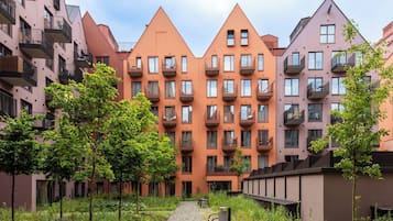 Eine Reihe moderner Apartmenthäuser mit Balkonen, einem zentralen Weg und umliegender Grünfläche.