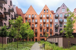 Eine Reihe moderner Apartmenthäuser mit Balkonen, einem zentralen Weg und umliegender Grünfläche.