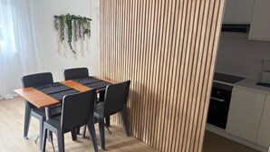 Et moderne køkken med et træspisebord og stole, en lodret træpanel og en hængende plante.