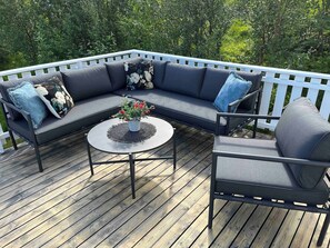 A deck with a sectional sofa, a round coffee table, and a single chair.