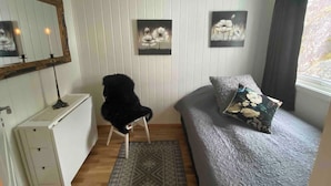 Un dormitorio con cama, una silla, un tocador y dos cuadros colgados en la pared.