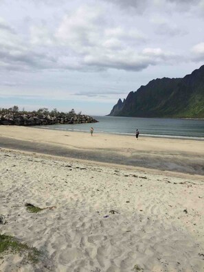 A beach with a rocky outcrop and a mountain in the background.