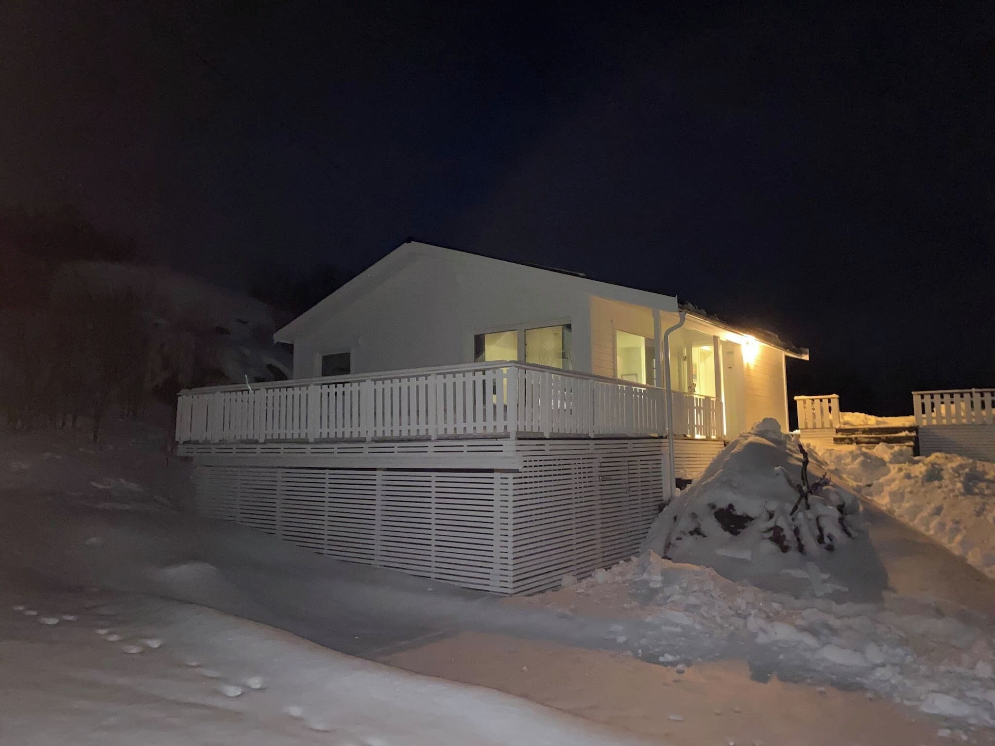 A single-story building with a balcony, surrounded by snow.